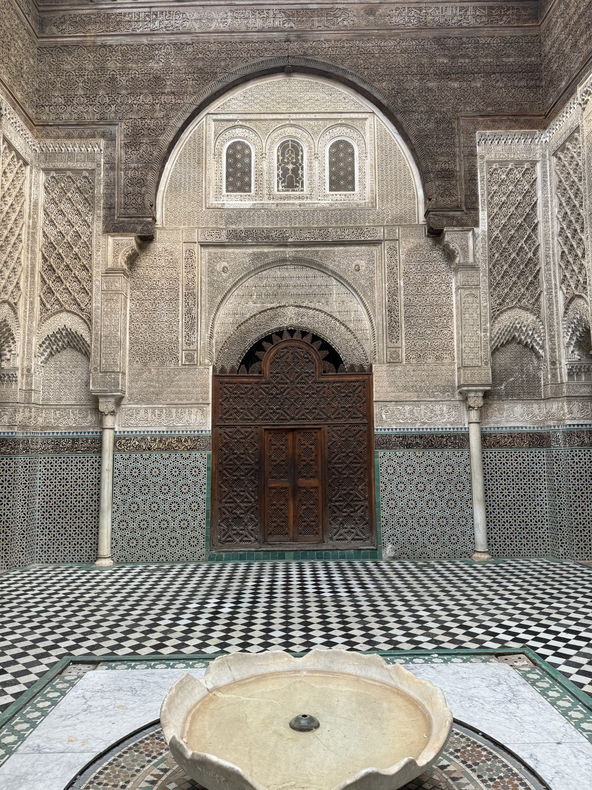 Ornate courtyard, zellige tiles and fountain at Al Attarine Madrasa in Fes Medina